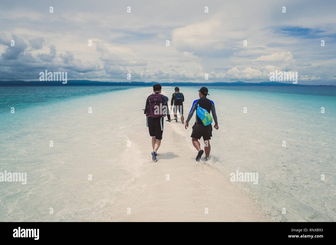 3 uomini cinesi a piedi su bianco Sandbar su Island Hopping Tour - Kalanggaman, Leyte, Filippine Foto Stock
