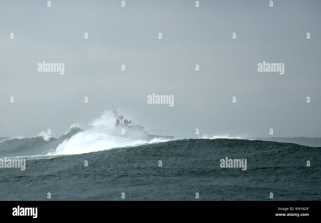 Una 47-piede la vita del motore equipaggio poteri attraverso un'onda durante la formazione di surf in spiedo di Clatsop vicino all'entrata del fiume Columbia all'Oceano Pacifico, Feb 15, 2019. L ingresso del Columbia River è riconosciuta come una delle migliori palestre di barca di salvataggio piloti a causa della sua coerente di mare mosso condizioni. Stati Uniti Coast Guard foto di Sottufficiali di prima classe Levi leggere. Foto Stock