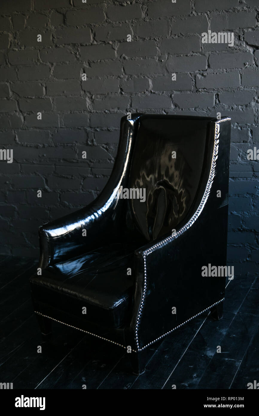 Moderna sedia nero su nero di un muro di mattoni in background. Il loft-stile. Foto Stock