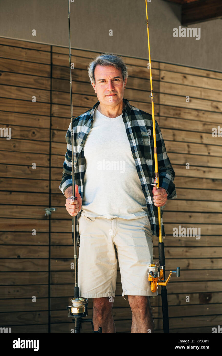 Uomo maturo holding canne da pesca Foto Stock