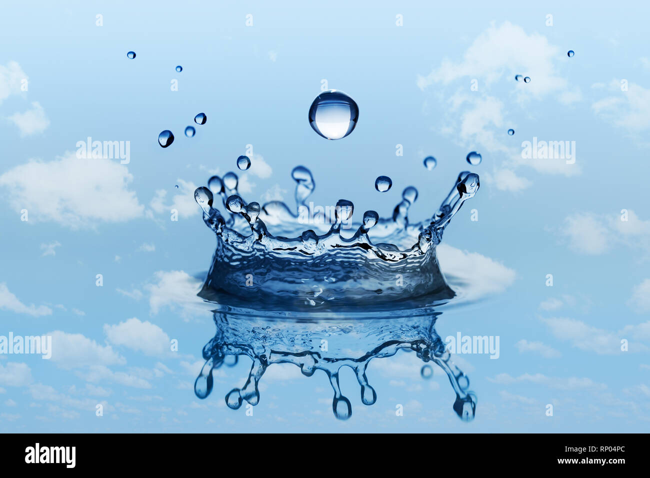 La caduta di una goccia di pioggia con spruzzi di acqua in forma di corona. Cielo blu e nuvole bianche come sfondo. Foto Stock