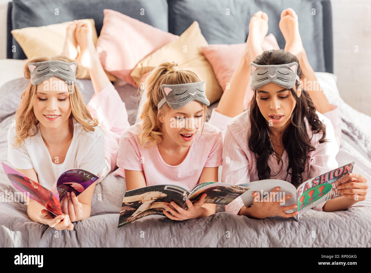 Belle ragazze multiculturale in maschere di pelo lettura di riviste durante  il pigiama party Foto stock - Alamy