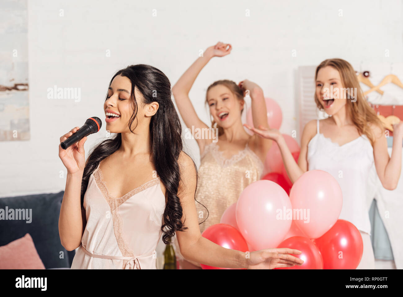 Belle ragazze multietnica nel canto nightwear karaoke in pigiama party in camera da letto Foto Stock