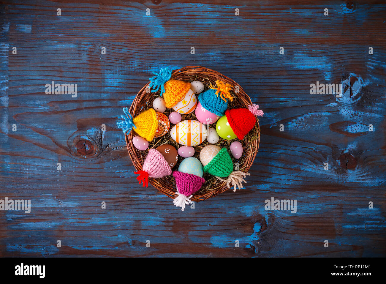 Pasqua cesto pieno di uova colorate su un blu sullo sfondo di legno Foto Stock
