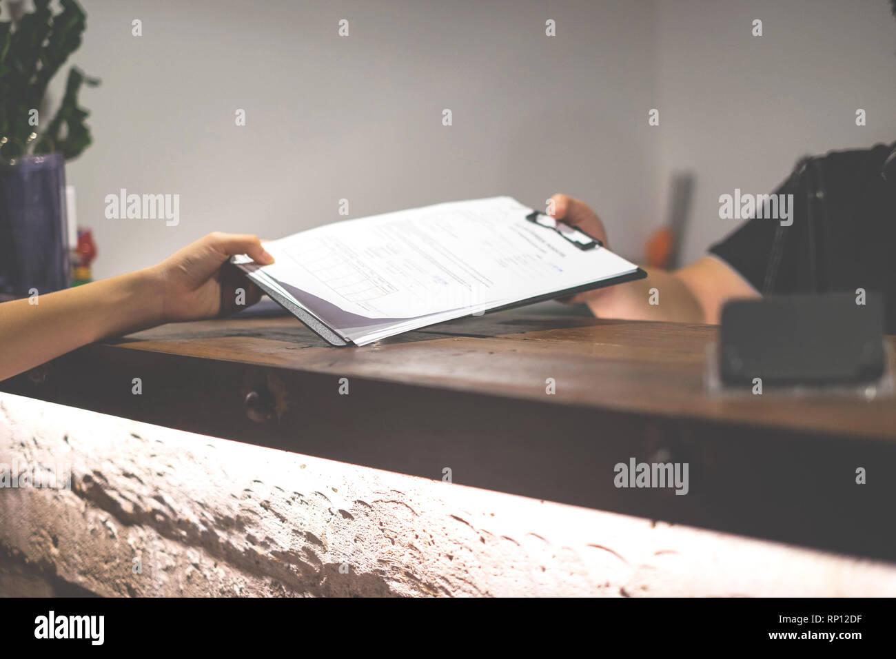 La receptionist ha inviato i documenti di valutazione per la firma e il riempimento forma processo di check-in.concetto di hotel. Foto Stock
