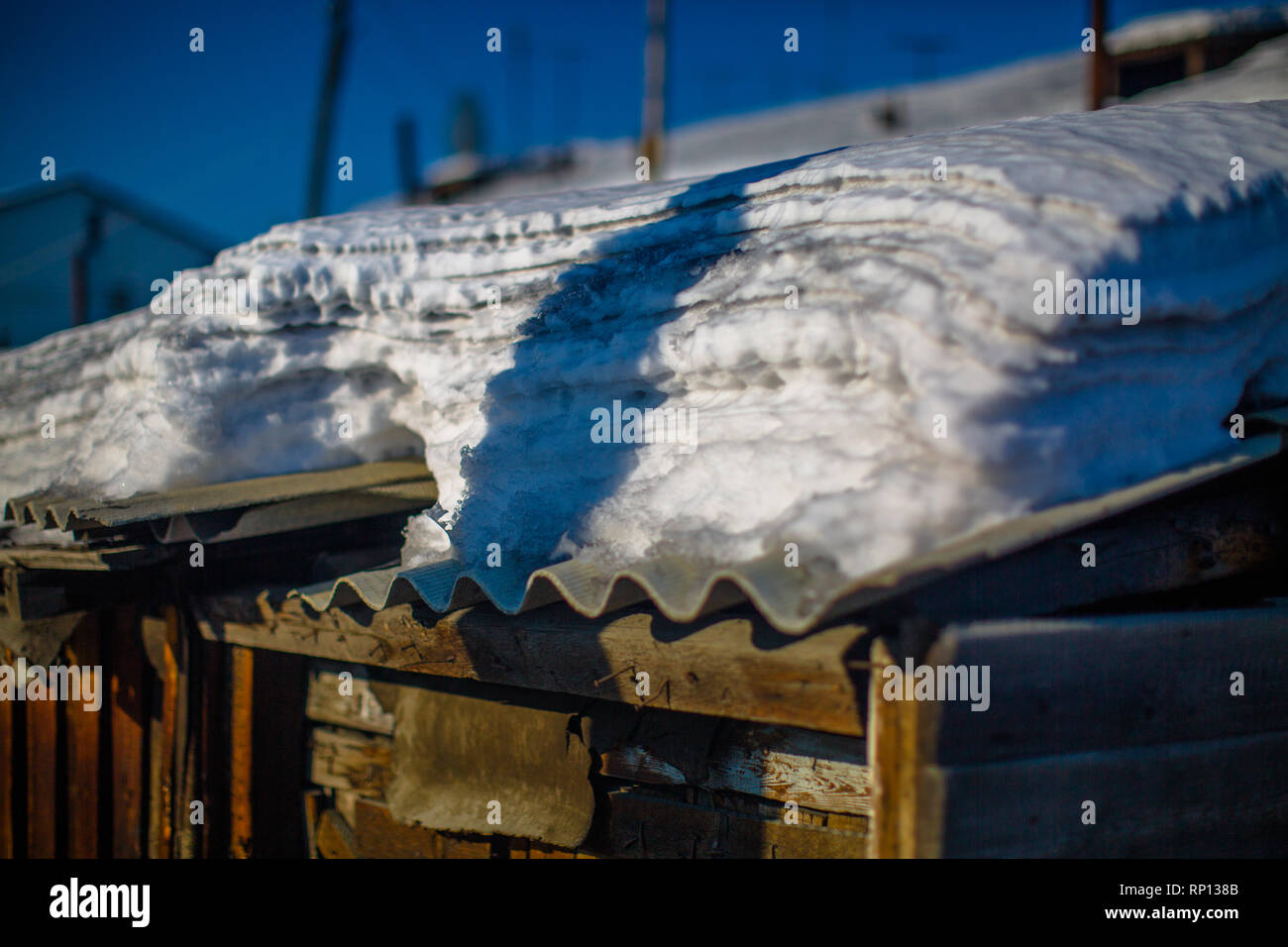 Una pletora di neve stratificata imbevuta su un tetto di ferro corrugato, Batagay, Russia Foto Stock