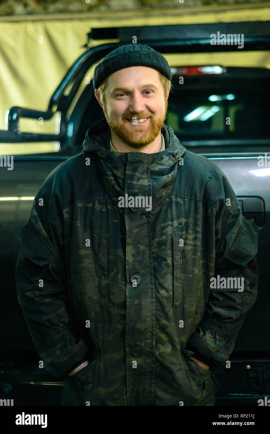 Ritratto di un uomo sorridente con la barba in piedi accanto a un camion Foto Stock