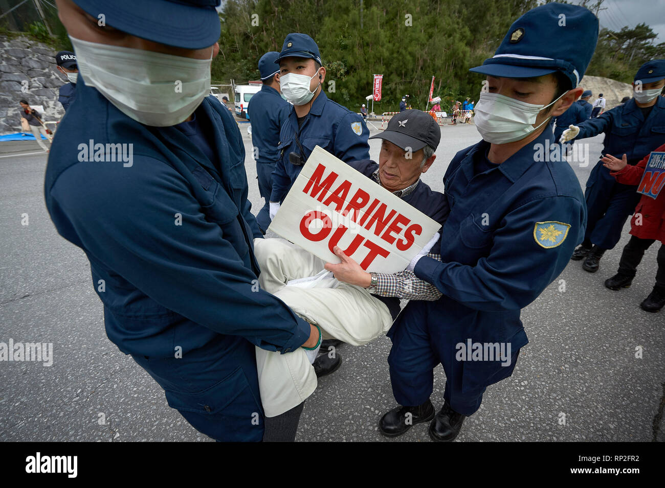 Henoko, Okinawa, in Giappone. 19 Feb, 2019. La polizia effettuare un uomo lontano dalla porta di un nuovo U.S. Marine Corps airbase essendo costruito a Henoko sull'isola giapponese di Okinawa. Decine di dimostranti, che vogliono la costruzione interrotta, doveva essere rimosso fisicamente in ordine per carrelli di riempire per immettere la base che è in fase di riempimento in una grande sezione di mare al fine di costruire un nuovo aeroporto. Credito: Paul Jeffrey/Alamy Live News Foto Stock