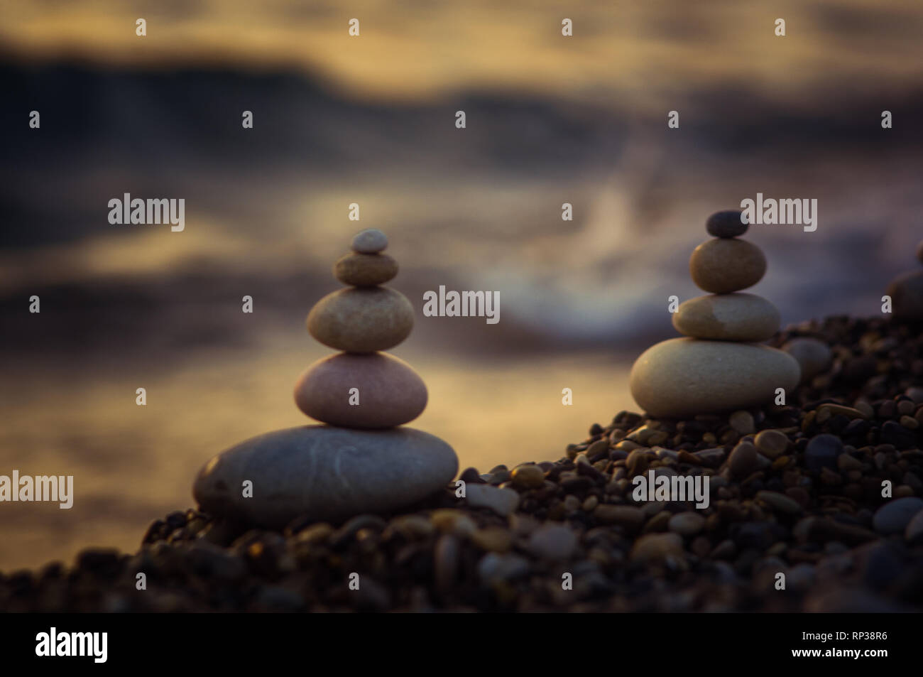 Piramide piegata Zen pietre ghiaia sul mare spiaggia al tramonto Foto Stock