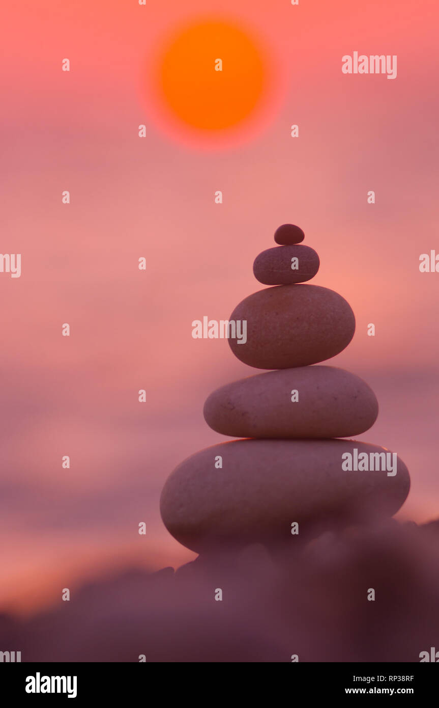 Piramide piegata Zen pietre ghiaia sul mare spiaggia al tramonto Foto Stock