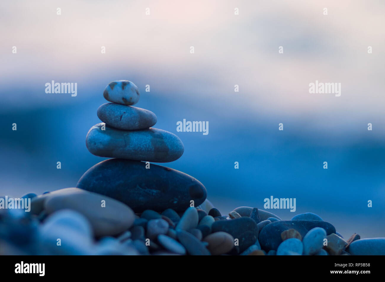 Piramide piegata Zen pietre ghiaia sul mare spiaggia al tramonto Foto Stock