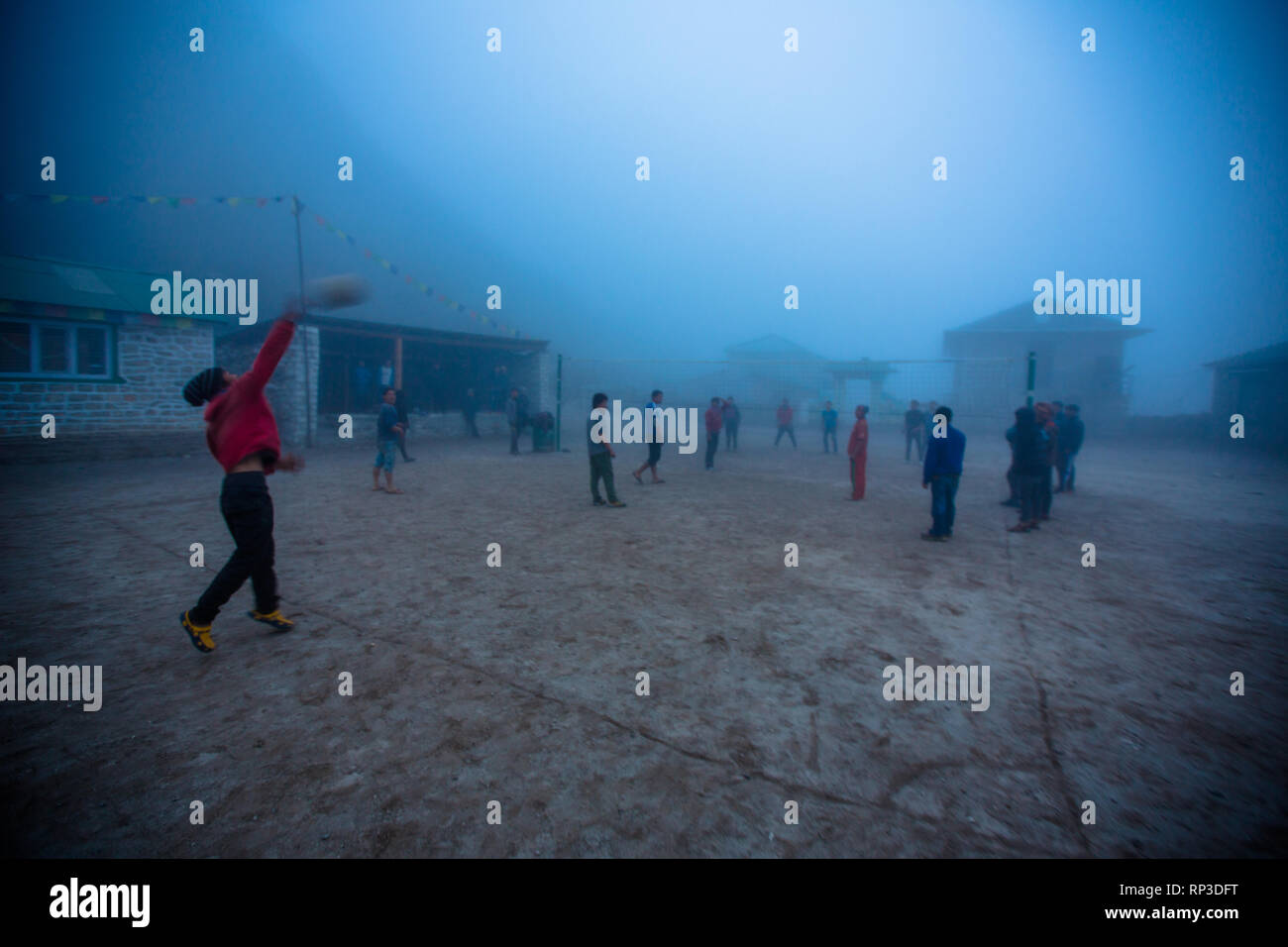 Ragazzi e ragazze giocare un gioco amatoriale di pallavolo nel pomeriggio di nebbia, Nepal Foto Stock
