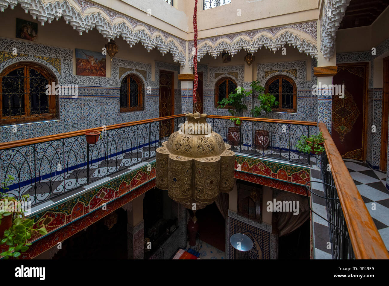 Cortile interno con pareti in piastrelle e pavimento di mosaico. Tradizionale e ornati arabesque colorate sculture di parete al di sopra di un arco nel riad marocchino Foto Stock