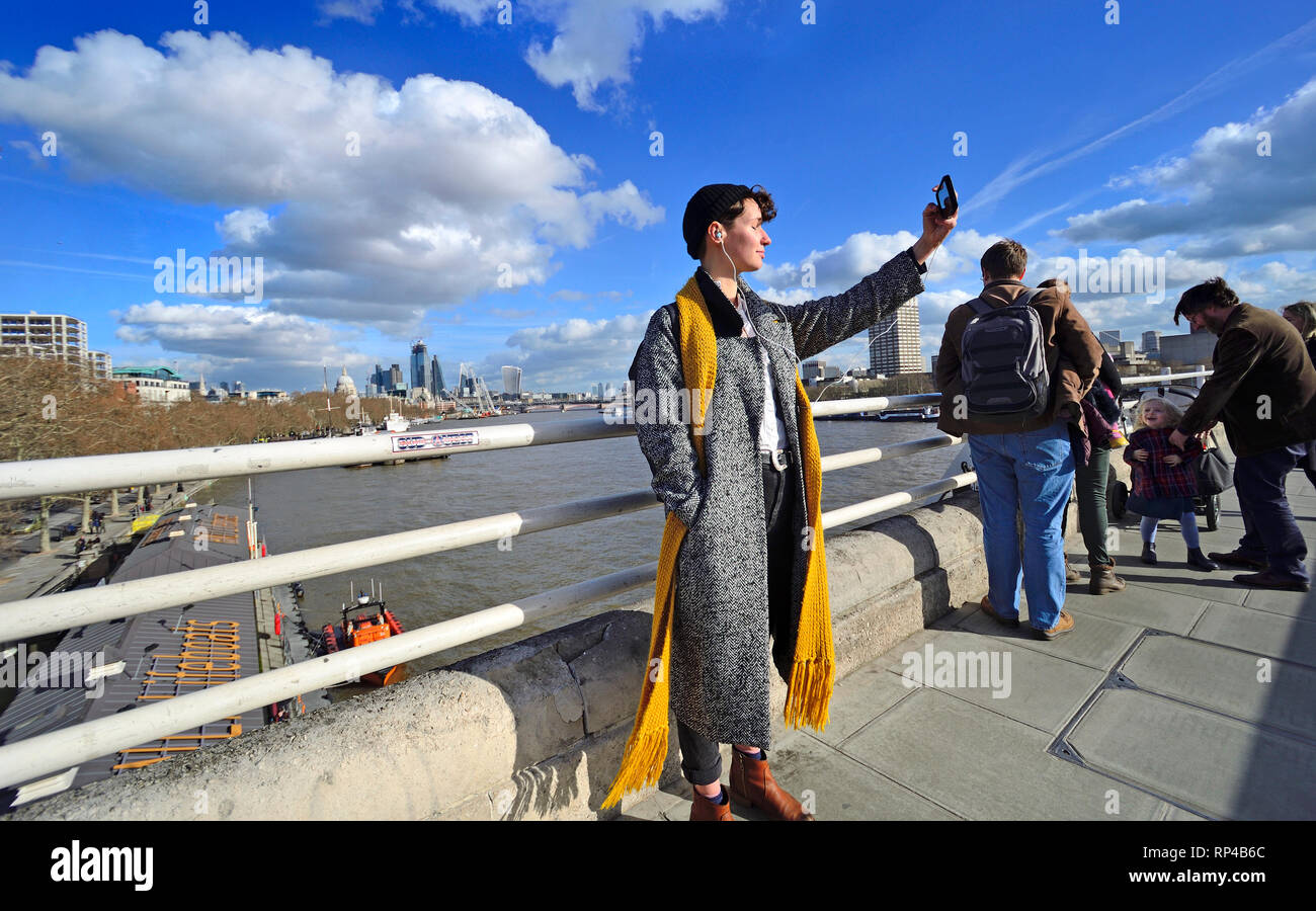 Londra, Inghilterra, Regno Unito. Giovane donna prendendo un selfie su Waterloo Bridge in una giornata di sole nel mese di febbraio 2019 Foto Stock