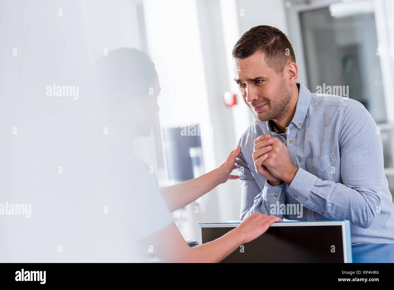 Paziente sconvolto guardando un infermiere con si prega di gesto Foto Stock