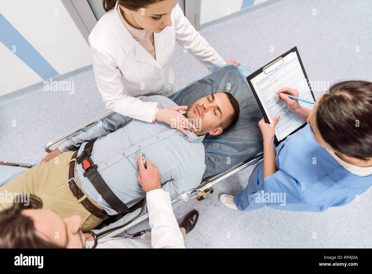 Vista superiore dei medici di trasportare il paziente in stato di incoscienza e di impulso di controllo Foto Stock