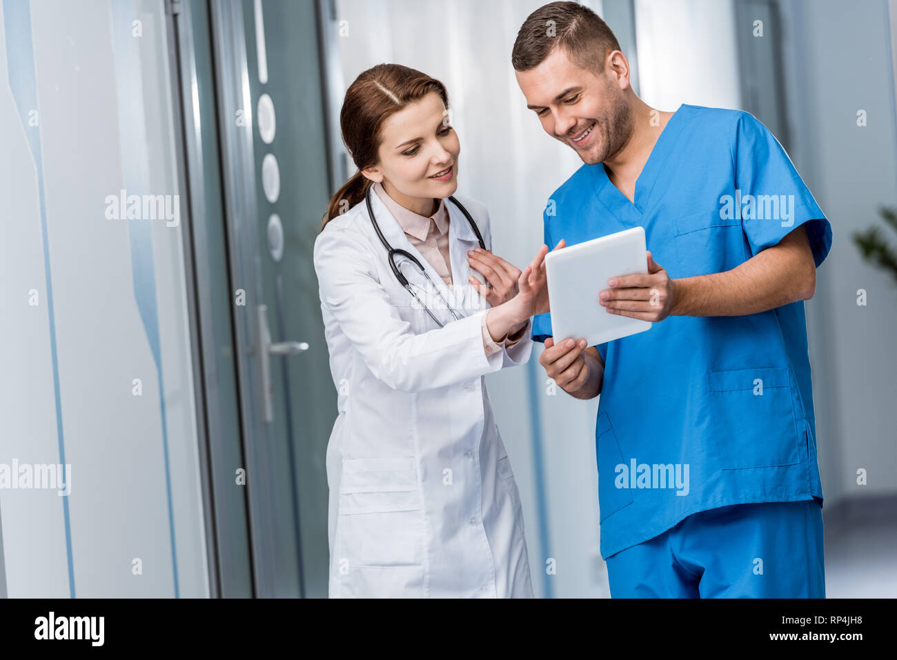 Sorridere i giovani medici in uniforme utilizzando tavoletta digitale Foto Stock