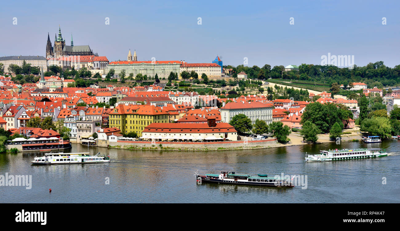 Fiume Vitava con barche, edifici e il castello di Praga, Repubblica Ceca Foto Stock