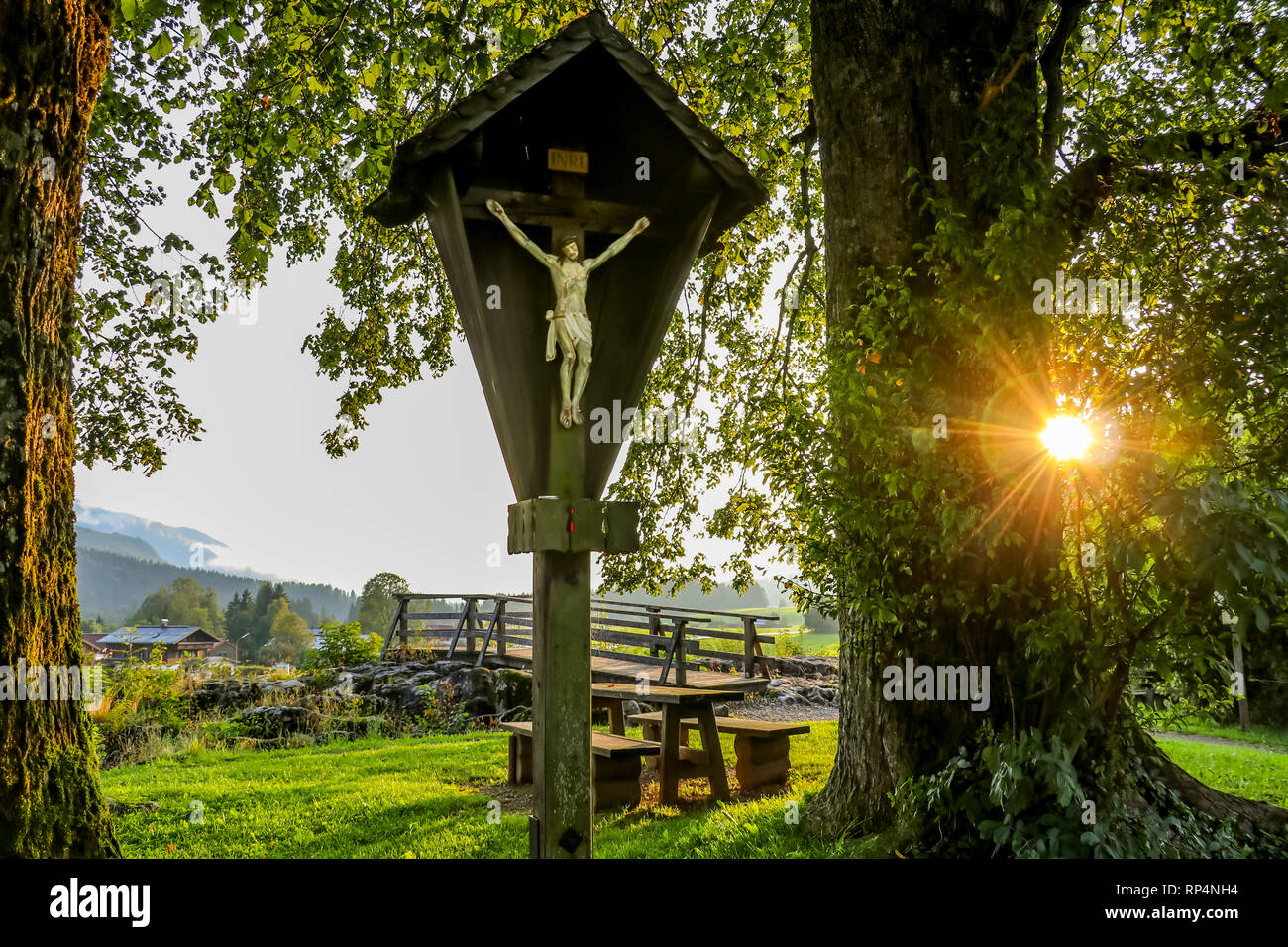 Croce di Gesù oltre la montagna via con il sole splendente raggio di luce, bavaria Reit im Winkl Foto Stock