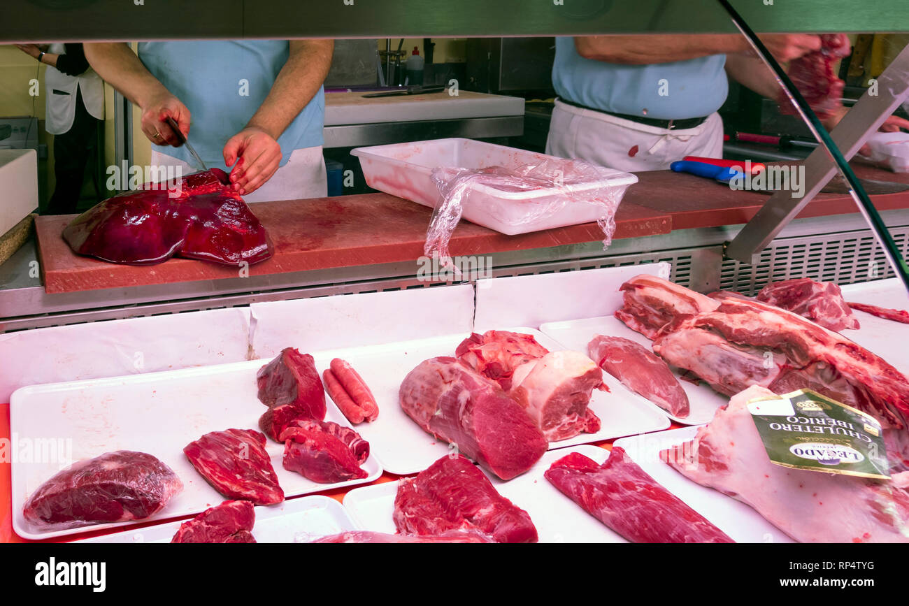 Un macellaio attentamente le strisce di sezionamento delle carni bovine fegato in un negozio a Siviglia, Spagna Foto Stock
