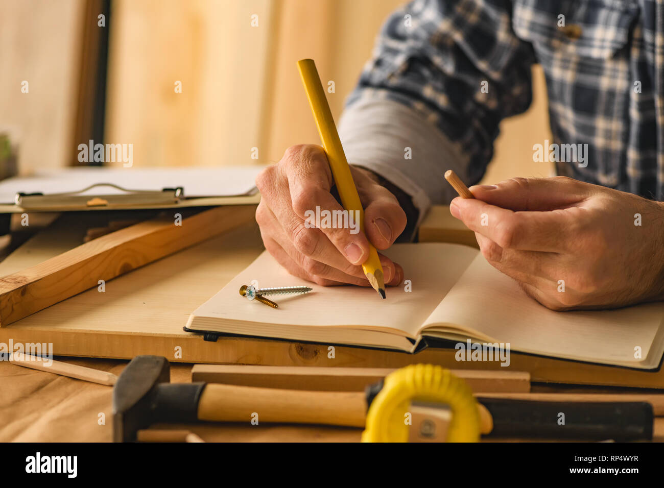 Carpenter la scrittura di note del progetto in small business workshop di falegnameria Foto Stock