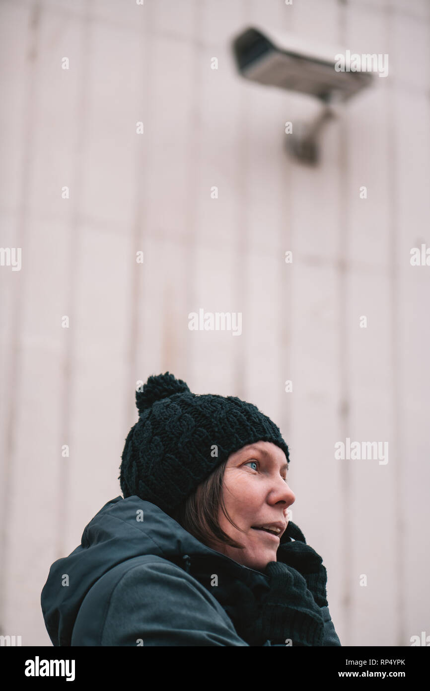 Donna che parla al telefono cellulare in strada con sorveglianza TVCC per il monitoraggio della telecamera Foto Stock
