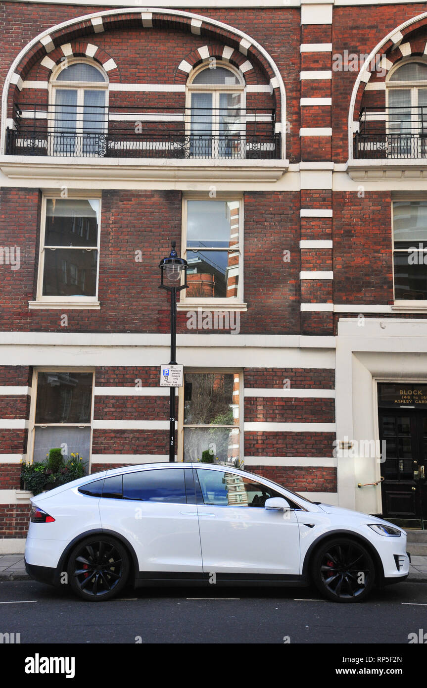 Un bianco Tesla Model X auto elettrica con ruote nere parcheggiato su una strada di Londra con un edificio di mattoni in background. Foto Stock