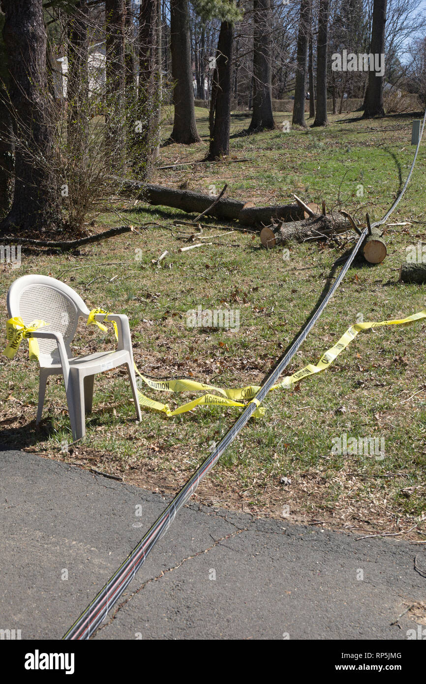 Linea elettrica verso il basso dalla tempesta e una sedia bianca con nastro di avvertenza Foto Stock
