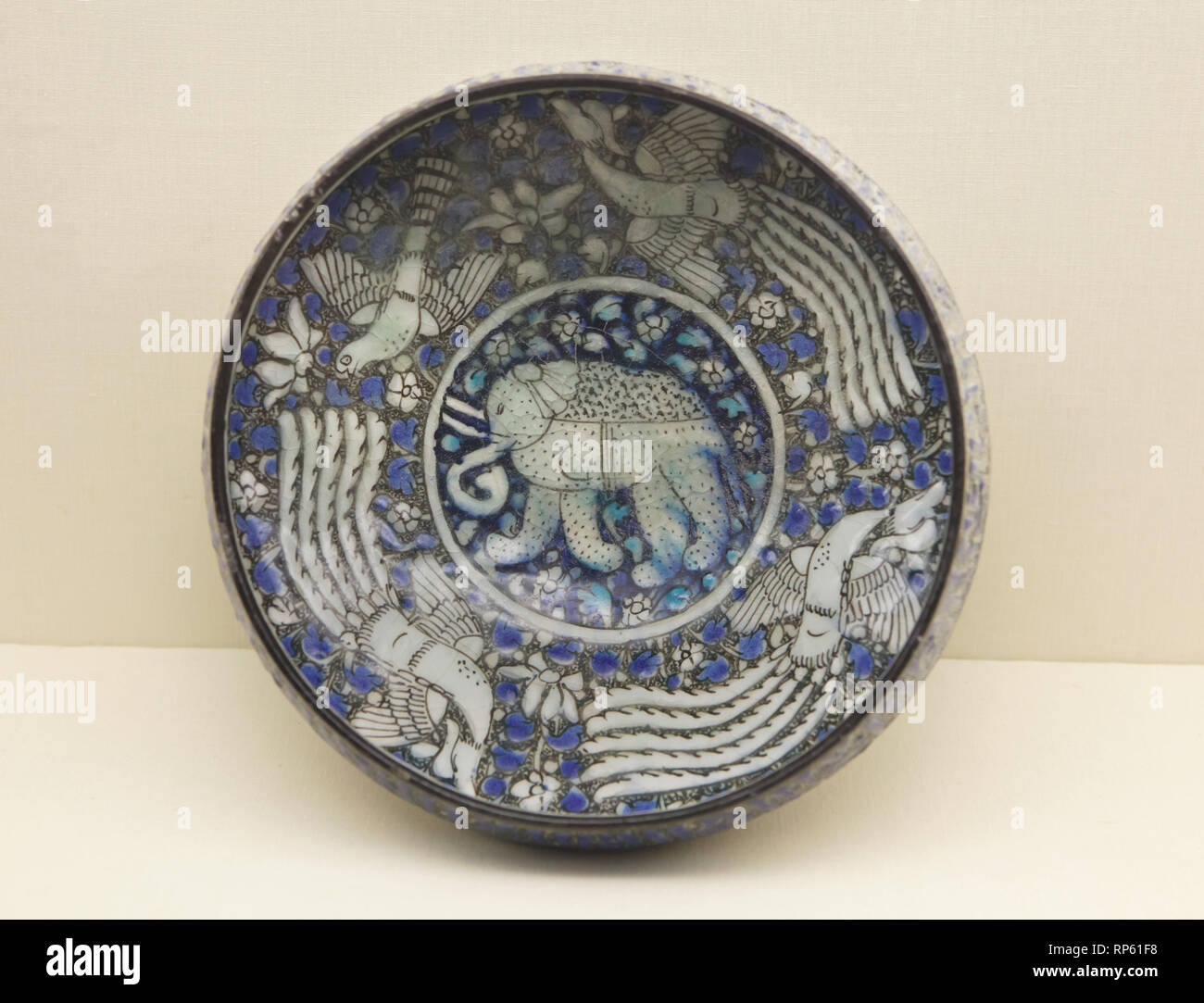 Fritware iraniano (pietra-incolla) ciotola con un elefante e tre fenici dipinto sotto lo smalto in stile Sultanabad (probabilmente da Kashan, Iran) datate dal XIV secolo in mostra al Museo Calouste Gulbenkian (Museu Calouste Gulbenkian) a Lisbona, Portogallo. Foto Stock