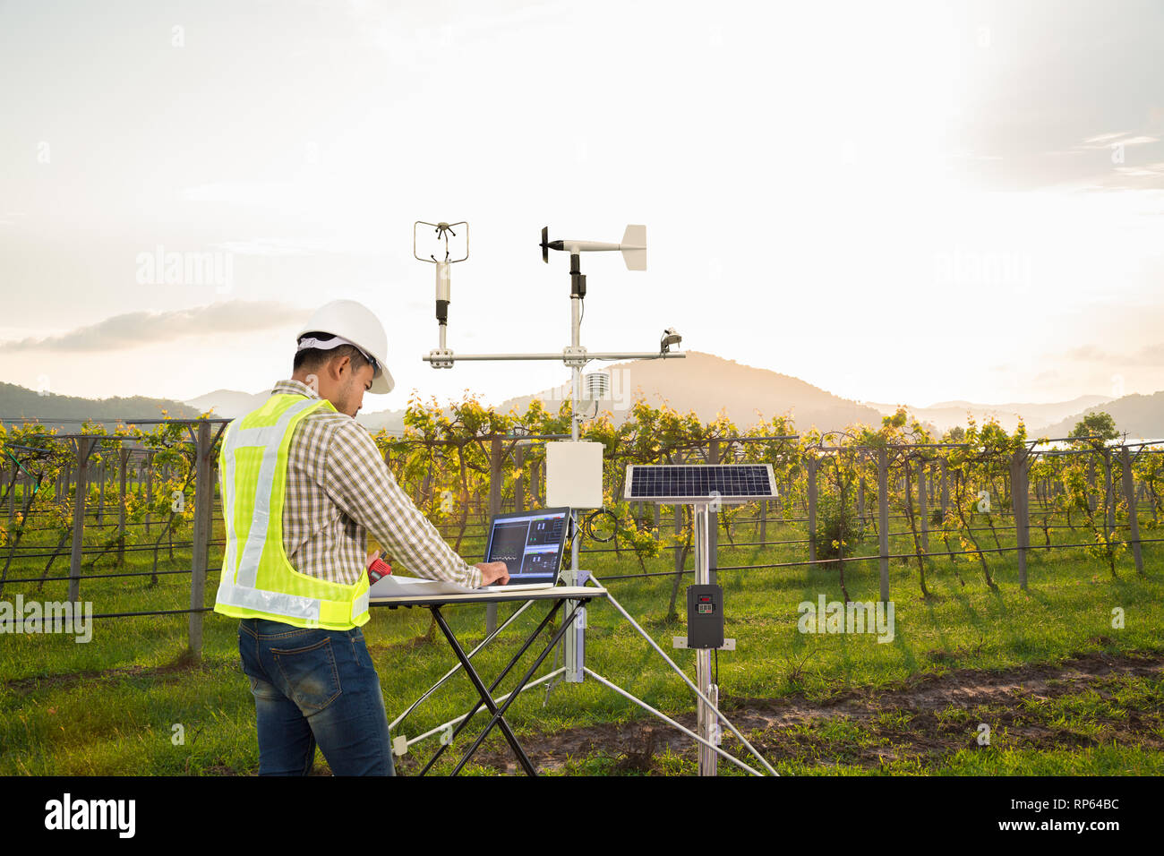 Agronomo utilizzando computer tablet di raccogliere dati con strumenti meteorologici per misurare la velocità del vento, temperatura e umidità e solare sistema cellulare Foto Stock