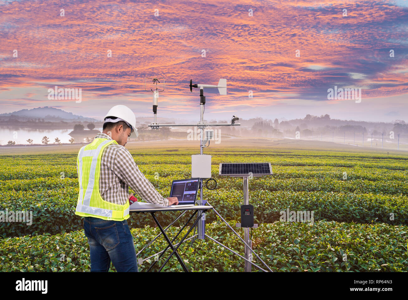 Agronomo utilizzando computer tablet di raccogliere dati con strumenti meteorologici per misurare la velocità del vento, temperatura e umidità e solare sistema cellulare Foto Stock