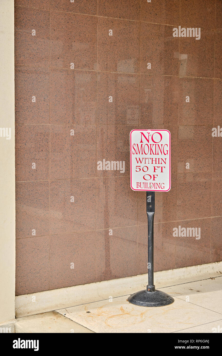 Il segno inviato accanto alla porta anteriore di edificio per uffici attenzione non fumare all'interno di 50 piedi dell'edificio, un segno di attenzione per non fumare in Montgomery AL, Stati Uniti d'America. Foto Stock