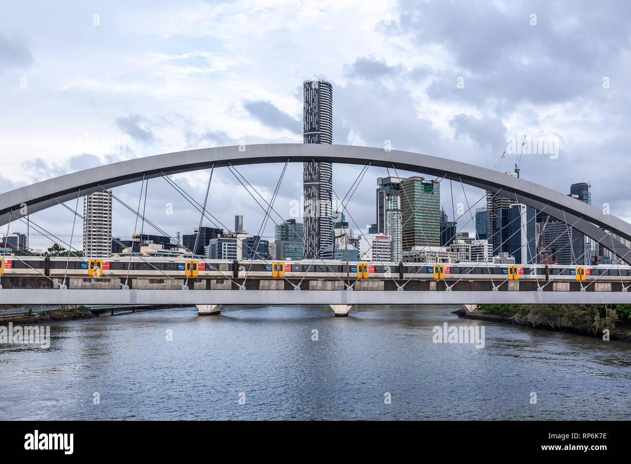 Il treno attraversa la Merivale ponte sul fiume Brisbane con un moderno alto edificio in background Foto Stock