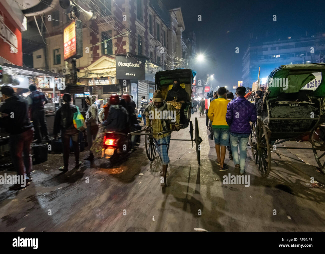 Tipico occupato atmosferica rumoroso la notte street scene in Kolkata con gente locale e rikshaw e street food fornitori. Foto Stock