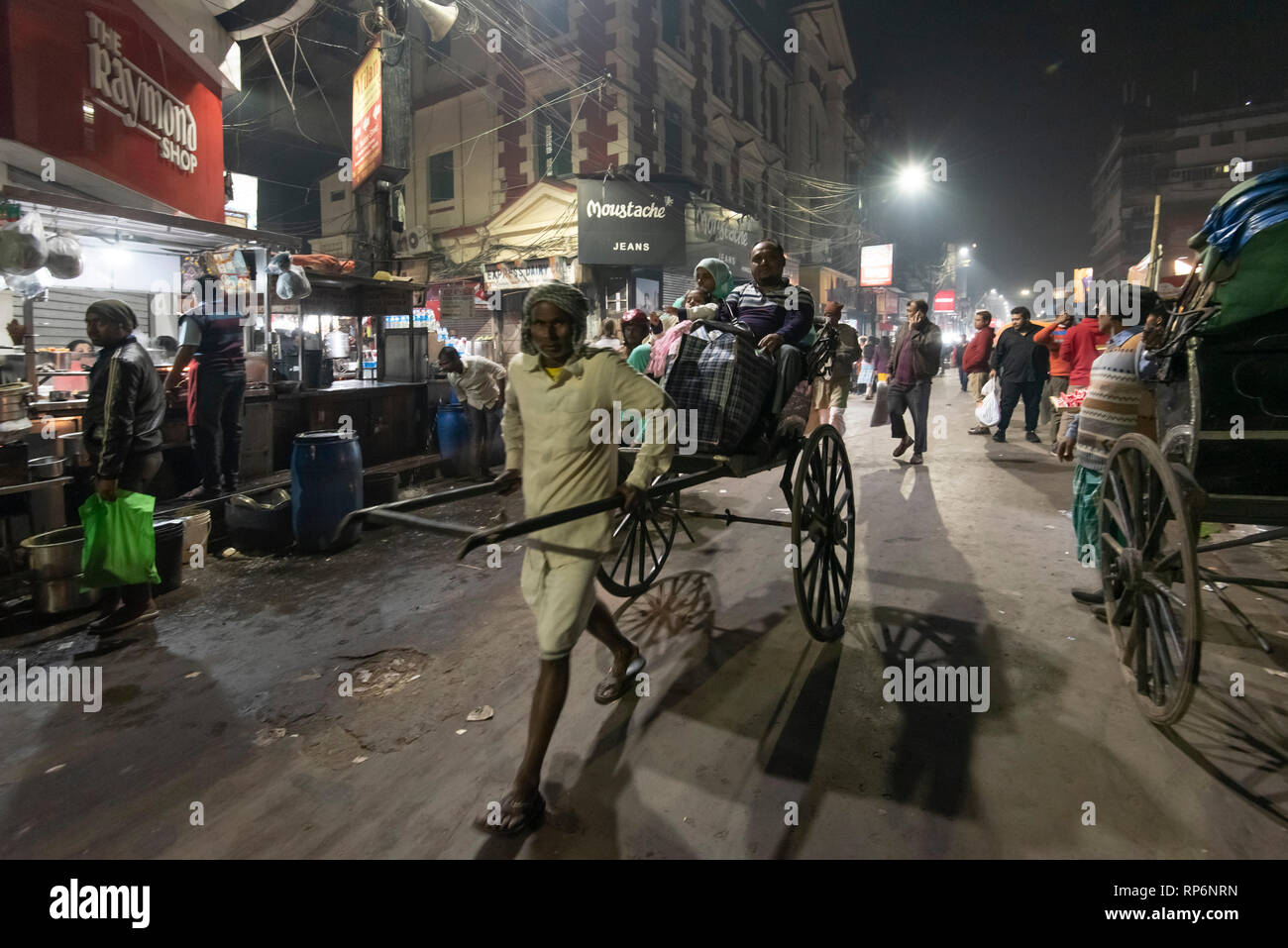 Tipico occupato atmosferica rumoroso la notte street scene in Kolkata con gente locale e rikshaw e street food fornitori. Foto Stock