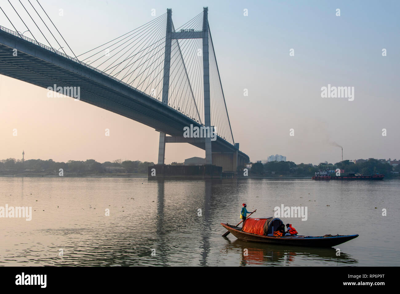 Una vista del Vidyasagar Setu ponte presi da Prinsep Ghat sul Fiume Hooghly al tramonto con una imbarcazione turistica in primo piano in Kolkata. Foto Stock