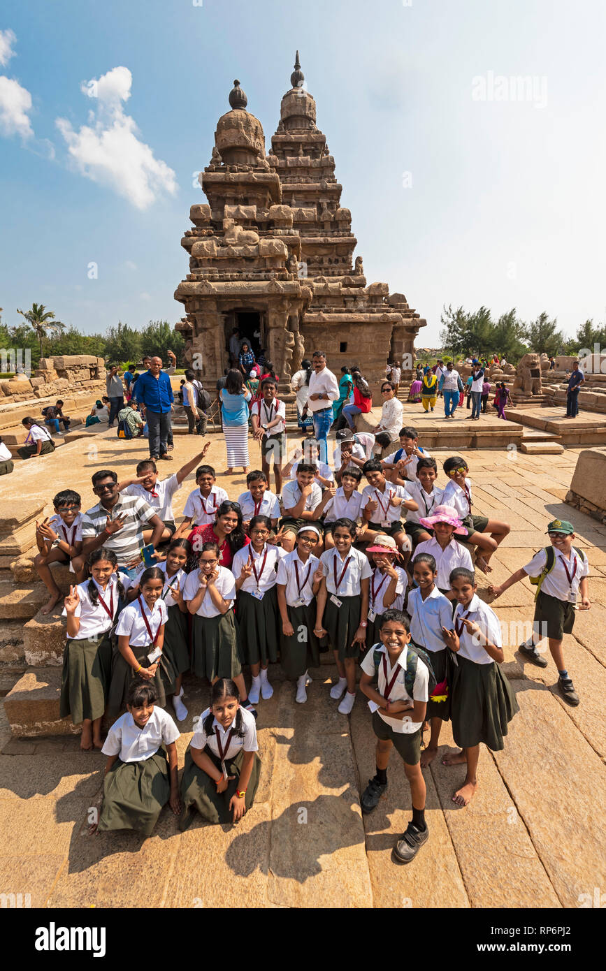 Un gruppo di Indiani locale scuola bambini pongono per la telecamera di fronte alla Riva tempio di Mahabalipuram con i turisti e la gente del luogo visitato. Foto Stock