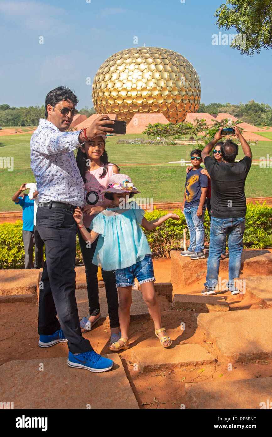 Persone locali e turisti tenendo selfies se la parte anteriore del Matrimandir - la cupola dorata monumento in Auroville - un concetto di stile di vita nei pressi di Pondicherry. Foto Stock
