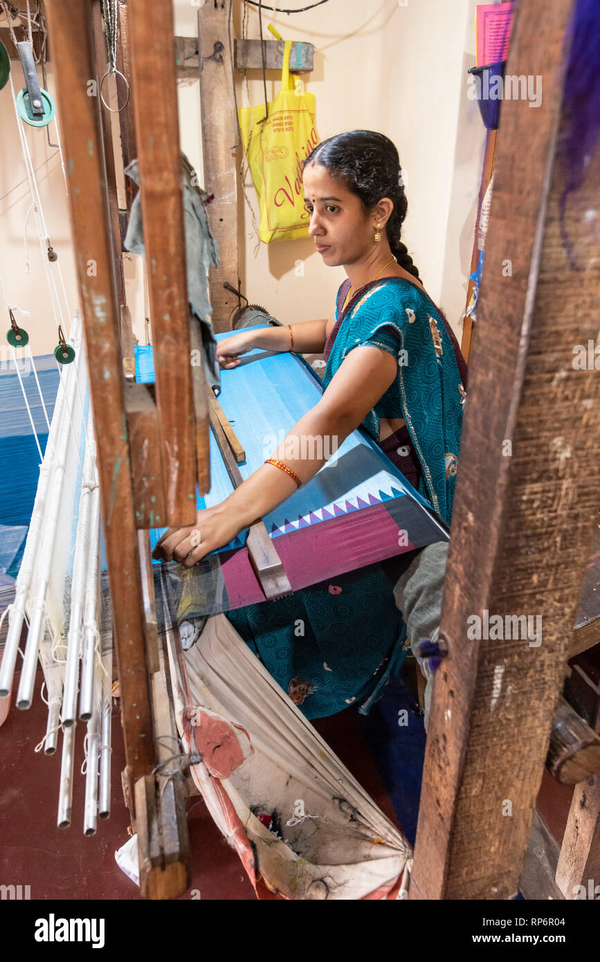 Un locale donna indiana che lavora con un tradizionale handloom rendendo il materiale di seta per un saree nel suo piccolo negozio. Foto Stock