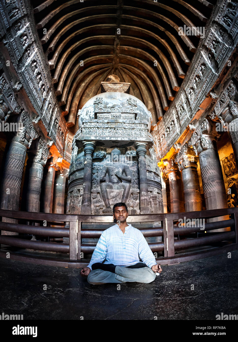 Uomo indiano di fare meditazione in lotus pongono vicino alla statua in antiche grotte di Ajanta vicino a Aurangabad, Maharashtra, India Foto Stock