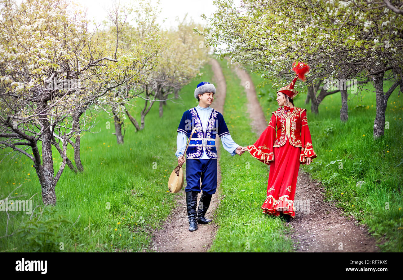 Matura in costume kazako a piedi attorno a fioritura primaverile apple giardino di Almaty in Kazakistan e in Asia centrale Foto Stock