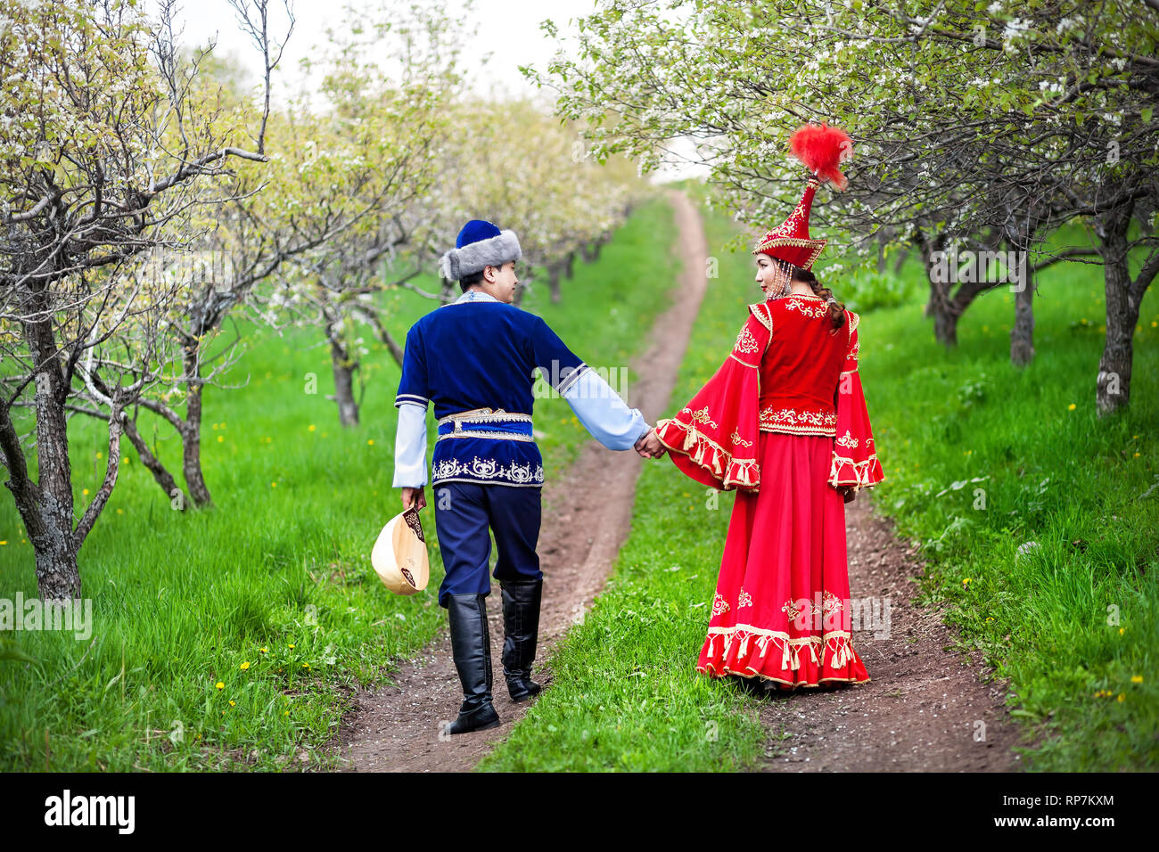 Matura in costume kazako a piedi attorno a fioritura primaverile apple giardino di Almaty in Kazakistan e in Asia centrale Foto Stock