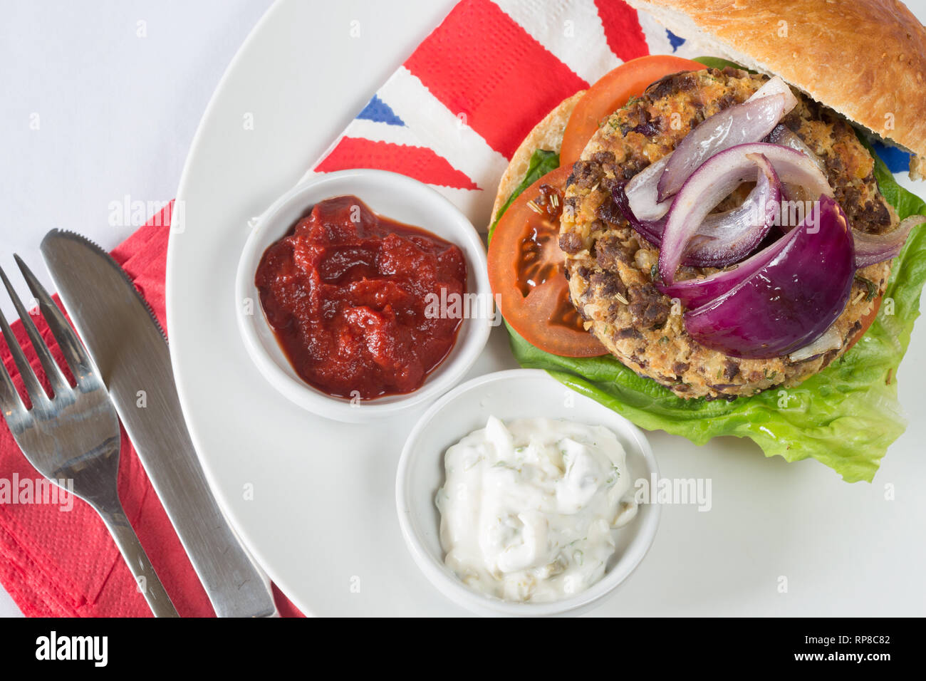 In casa di Quorn burger in un panino a lievitazione naturale con lattuga, pomodoro, cipolla rossa, e servita con ketchup e yogurt di soia salse. Foto Stock