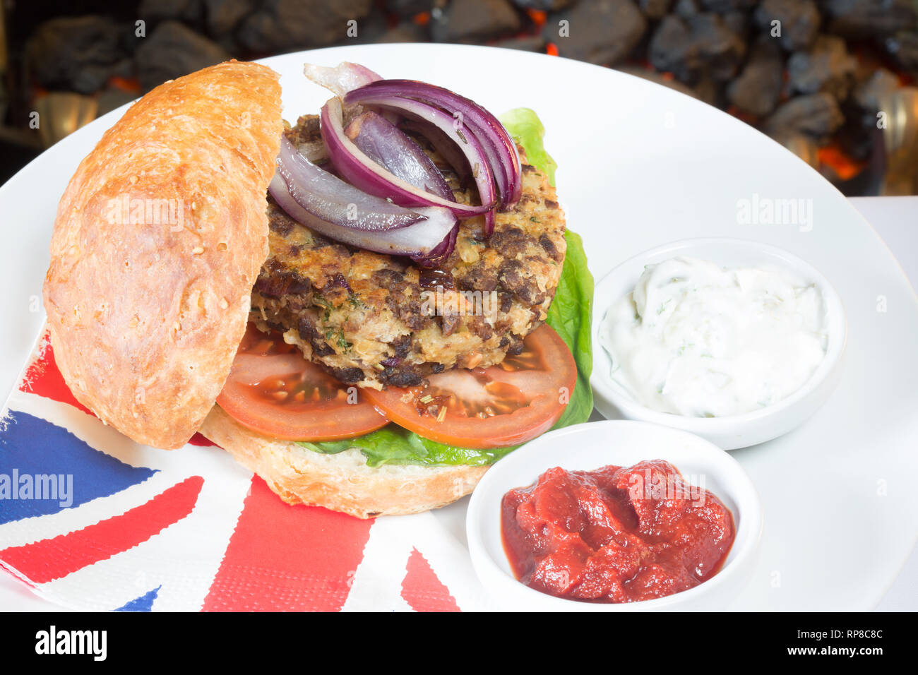 In casa di Quorn burger in un panino a lievitazione naturale con lattuga, pomodoro, cipolla rossa, e servita con ketchup e yogurt di soia salse. Foto Stock