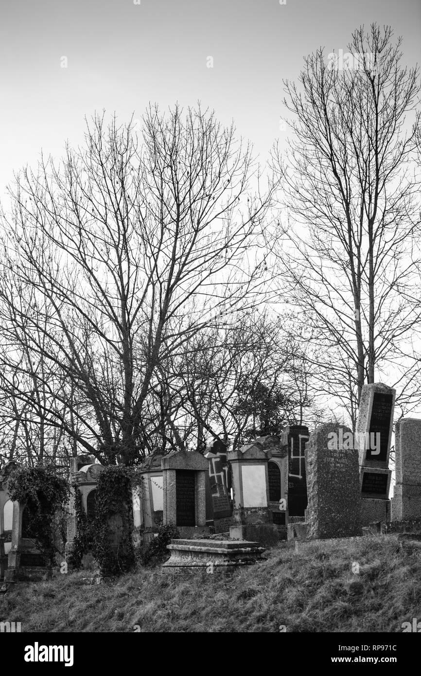 L'immagine verticale del soggetto ad atti vandalici tombe con simboli nazisti in blu spray-dipinte sulle tombe danneggiato - Cimitero Ebraico in Quatzenheim vicino a Strasbourg, Francia Foto Stock
