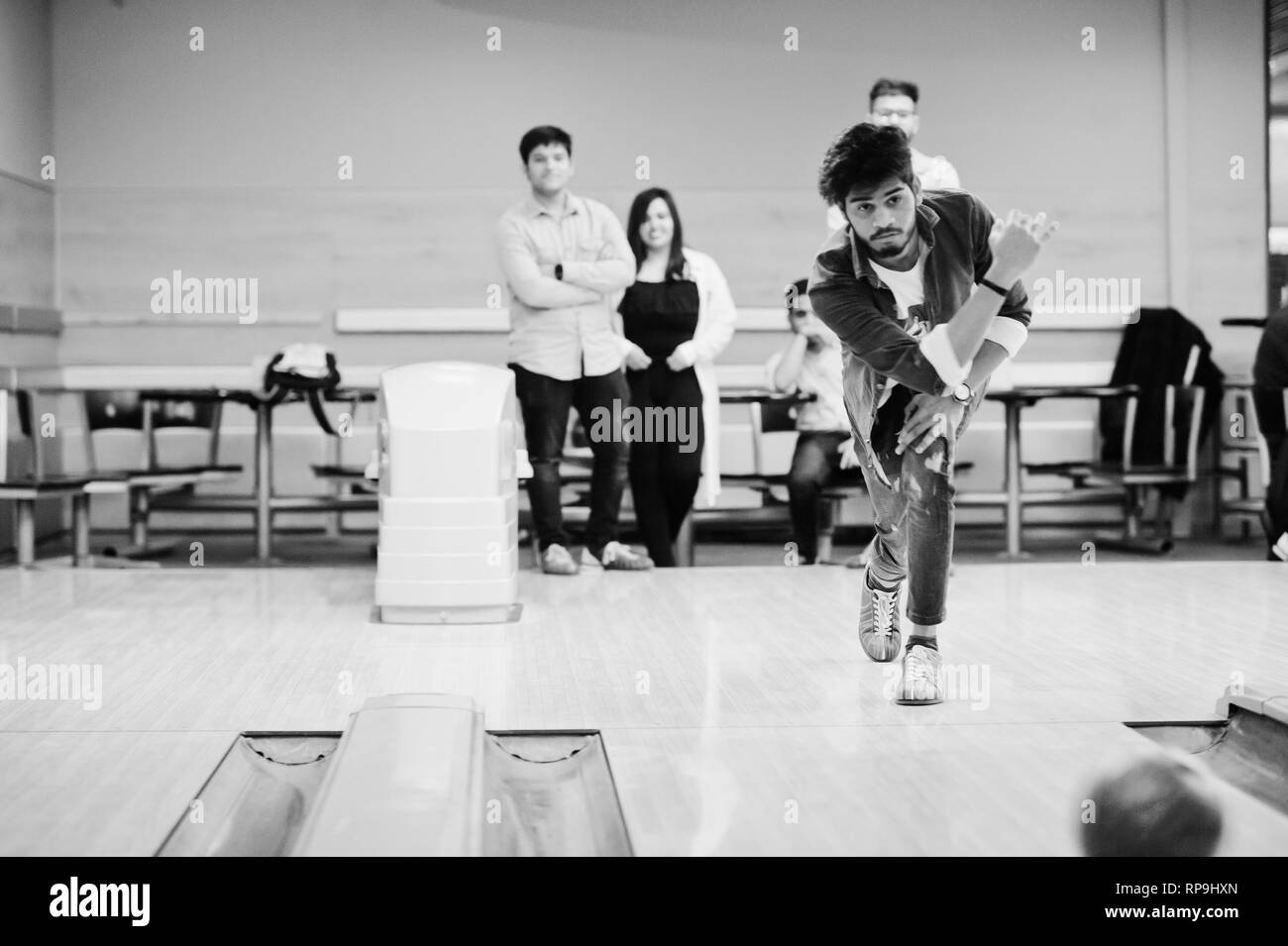 South Asian uomo in jeans shirt permanente al bowling e buttare la palla. Foto Stock