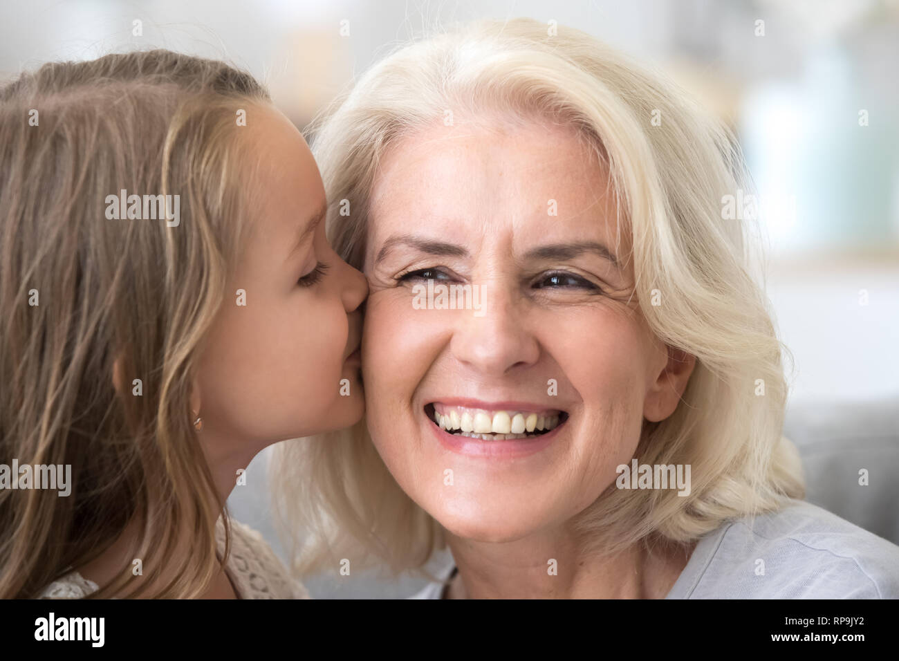 Carino piccolo nipote kissing eccitato nonna sulla guancia Foto Stock