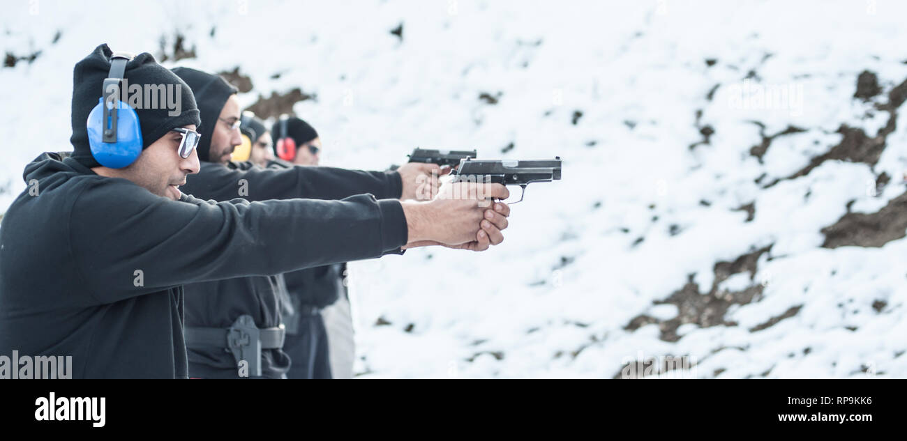 Gruppo di pratica civile pistola spara sul bersaglio all'aperto sul poligono di tiro. Team civili addestramento alle armi Foto Stock