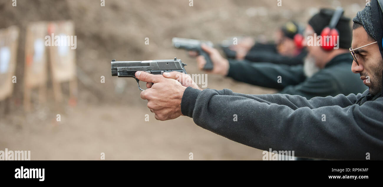 Gruppo di pratica civile pistola spara sul bersaglio all'aperto sul poligono di tiro. Team civili addestramento alle armi Foto Stock