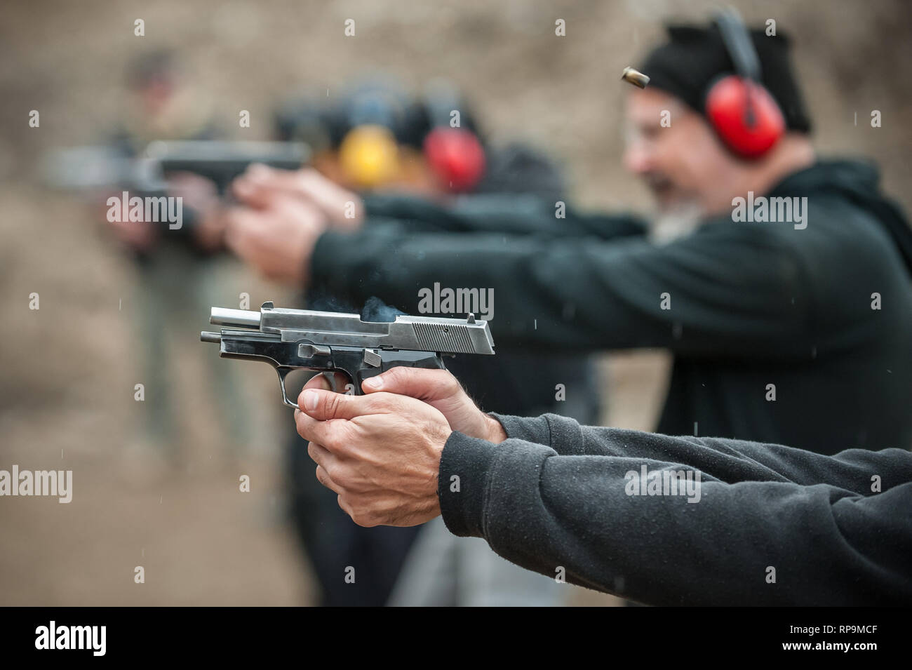 Gruppo di pratica civile pistola spara sul bersaglio all'aperto sul poligono di tiro. Team civili addestramento alle armi Foto Stock
